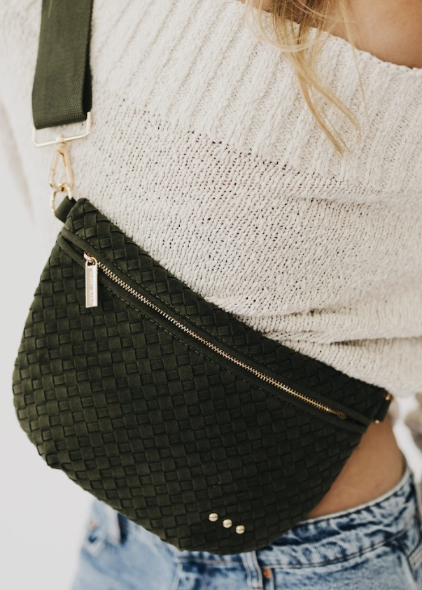 Woman wearing cream sweater with suede olive bum bag on white background