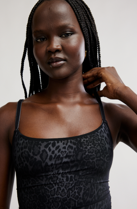 Woman wearing a black leopard print top against a plain background