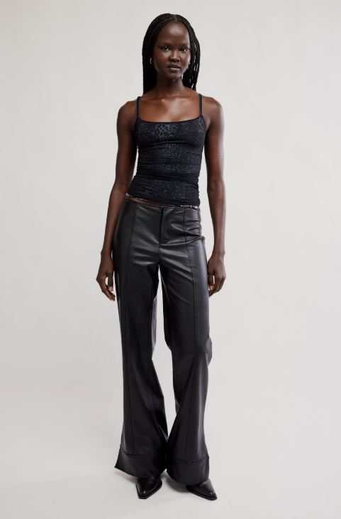 Woman wearing a black tank top and wide-leg pants on a white background