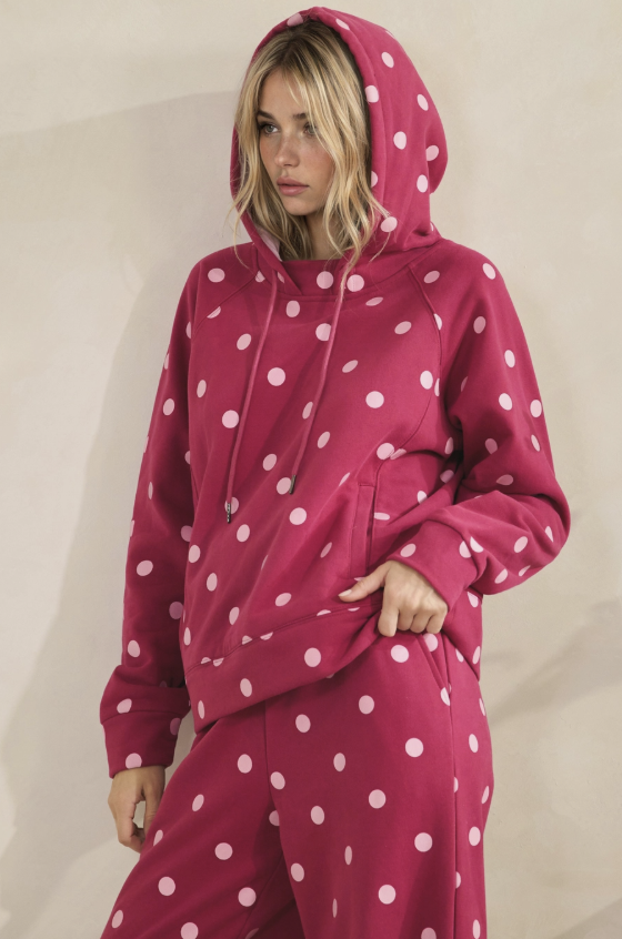 Woman wearing matching magenta and pink polka dot hoodie and pants on plain background