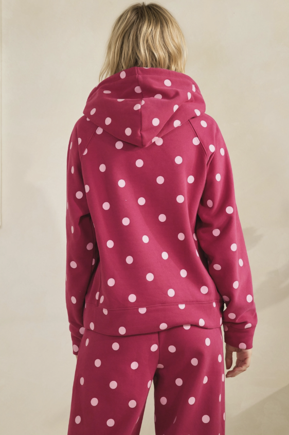 A person shown from the back wearing a matching pink hoodie and sweatpants set with a white polka dot pattern, against a plain beige background.