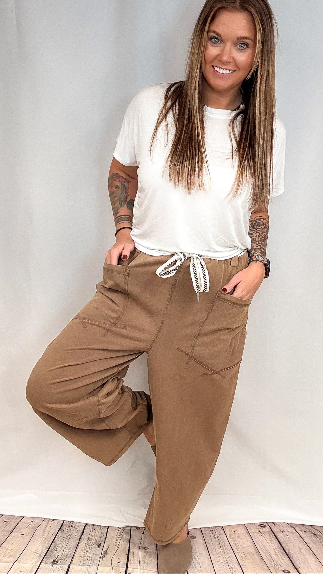Woman wearing white short sleeve shirt and brown barrel pants on white background
