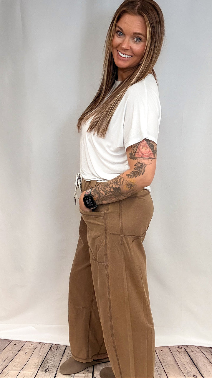Woman wearing white short sleeve shirt and brown barrel sweatpants on white background