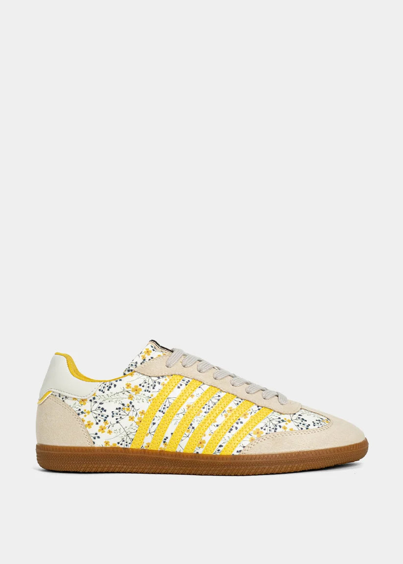 Sneaker with yellow and floral accents on plain background