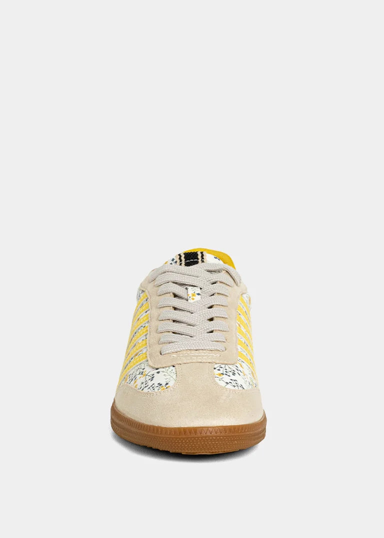 Sneaker with yellow and floral accent on plain background
