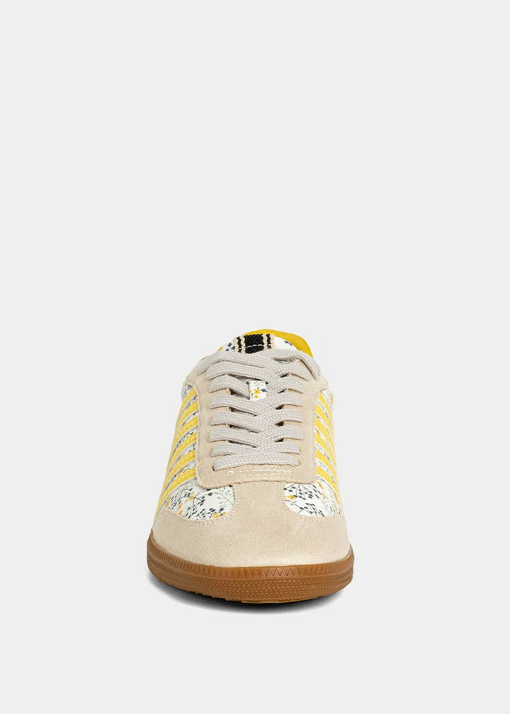 Sneaker with yellow and floral accent on plain background