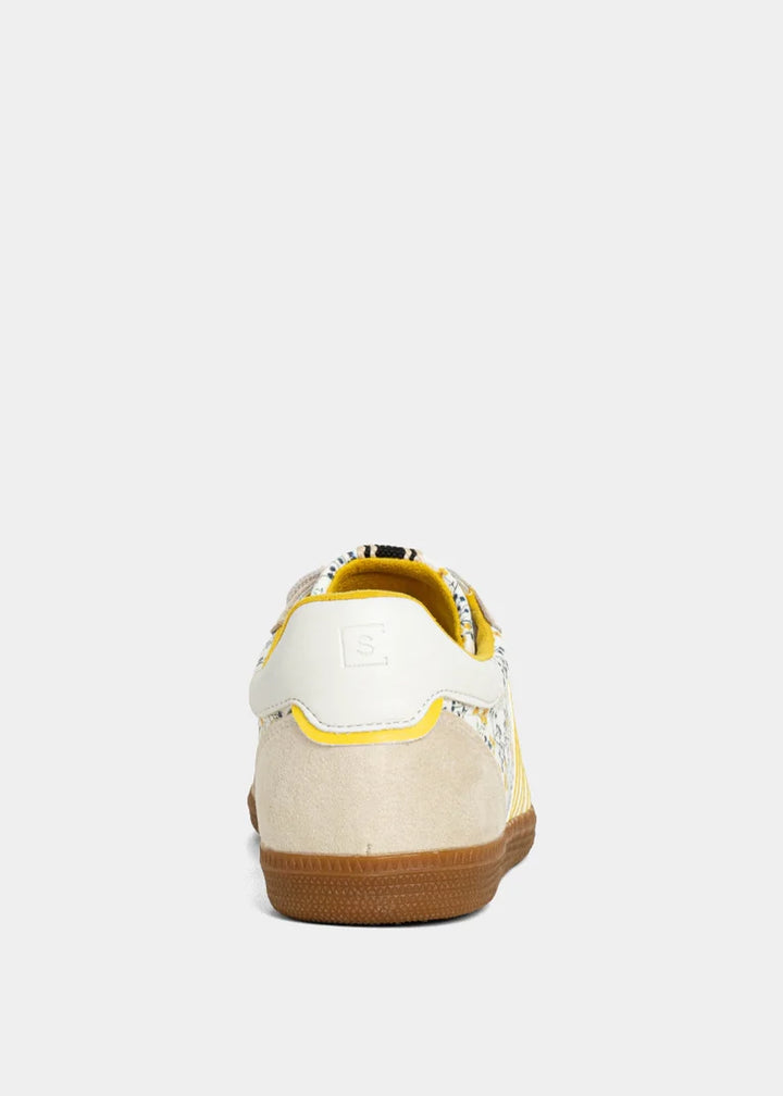 Sneaker with yellow and floral accents on plain background
