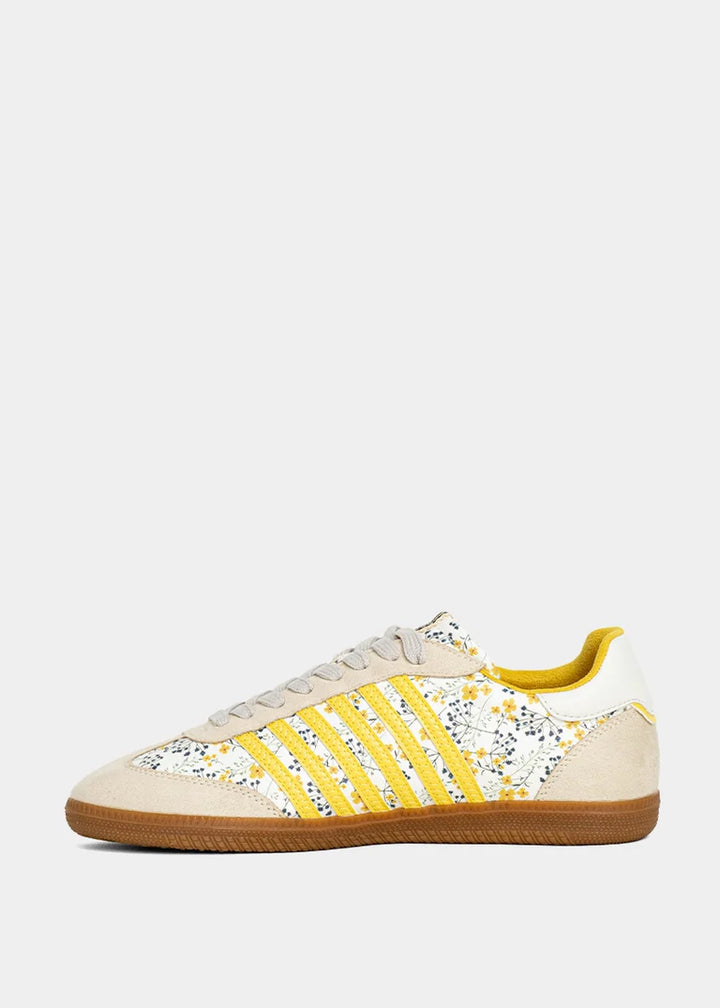 Sneaker with yellow and floral accents on plain background