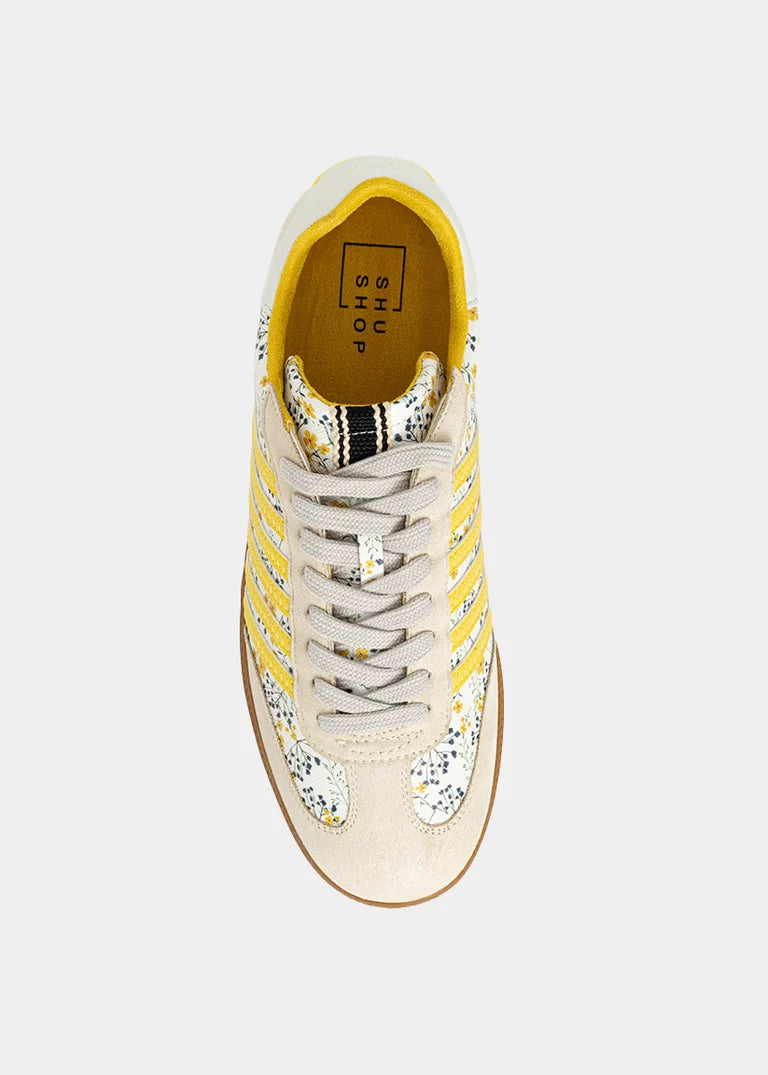 Sneaker with yellow and floral accents on plain background