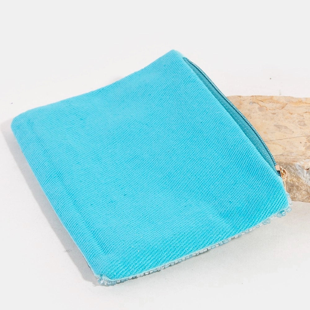 Turquoise coin purse on a white surface with a wooden block in the background