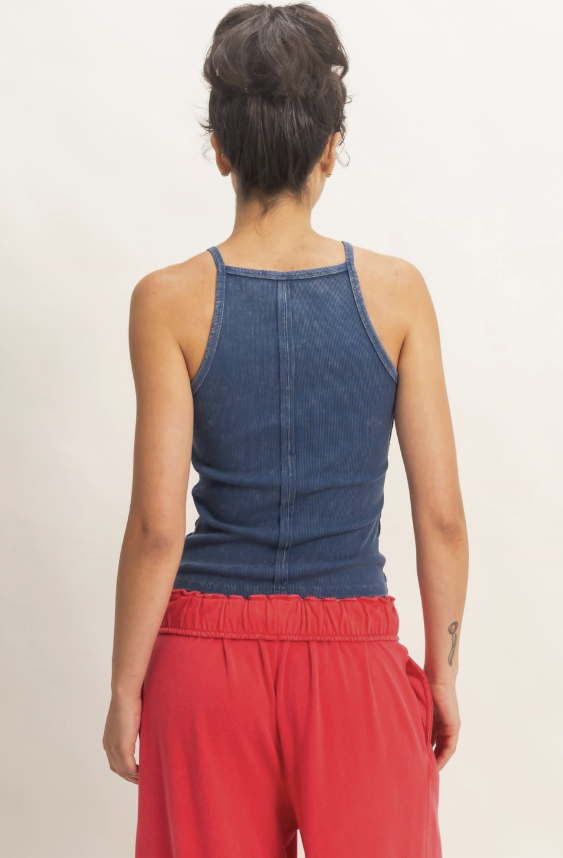 Person wearing a blue tank top and red pants on a plain background