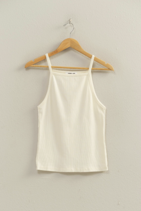 Beige tank top on a wooden hanger against a plain wall