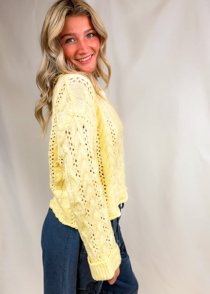 Woman wearing yellow cable knit henley pullover on plain background