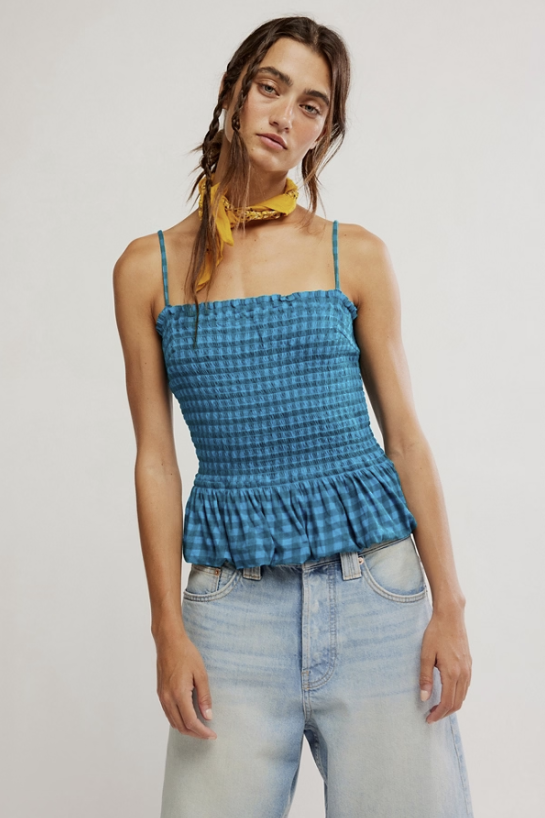 Woman wearing a blue checkered top and light blue jeans against a plain background