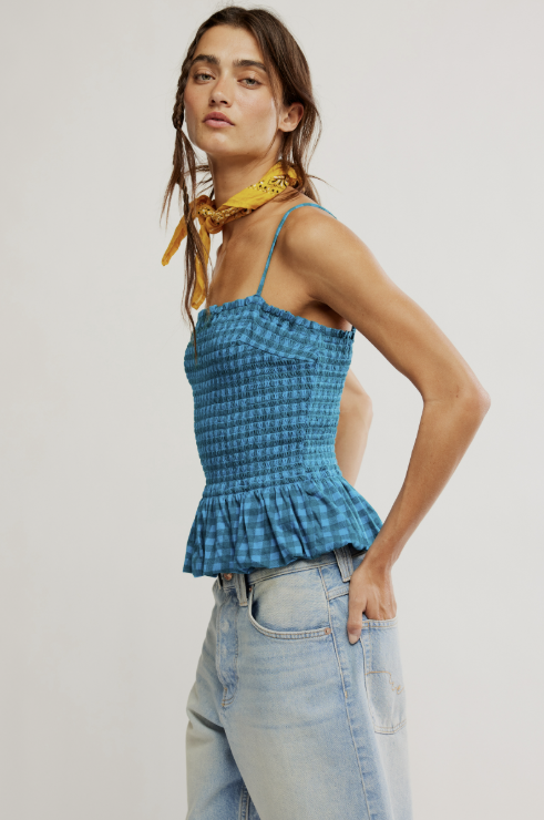 Woman wearing a blue checkered top and light blue jeans with a yellow scarf on a white background