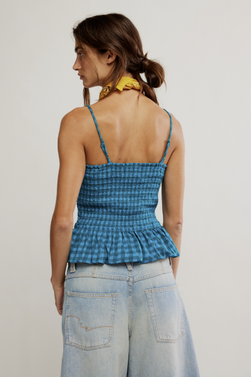 Woman wearing a blue checkered top and light blue jeans against a plain background