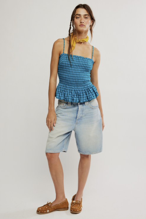 Woman wearing a blue checkered top and light denim shorts on a white background