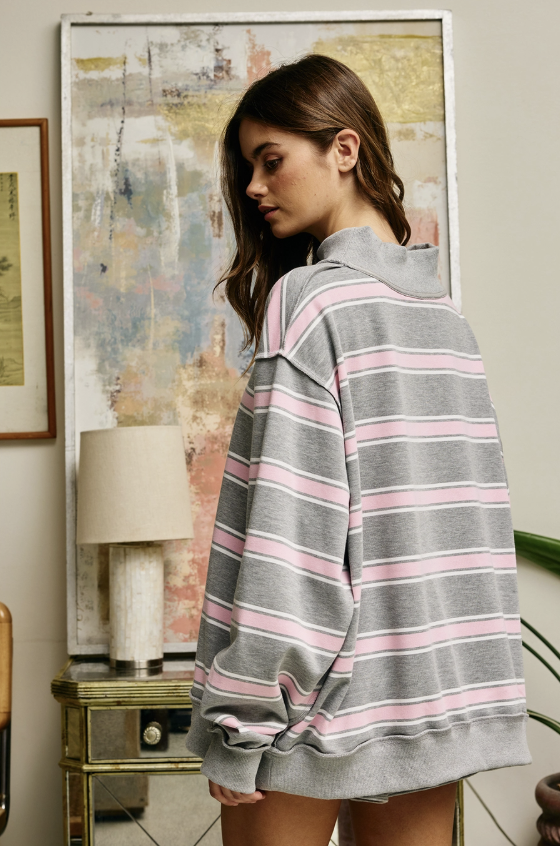 Woman wearing pink and grey striped mock neck sweatshirt standing indoors