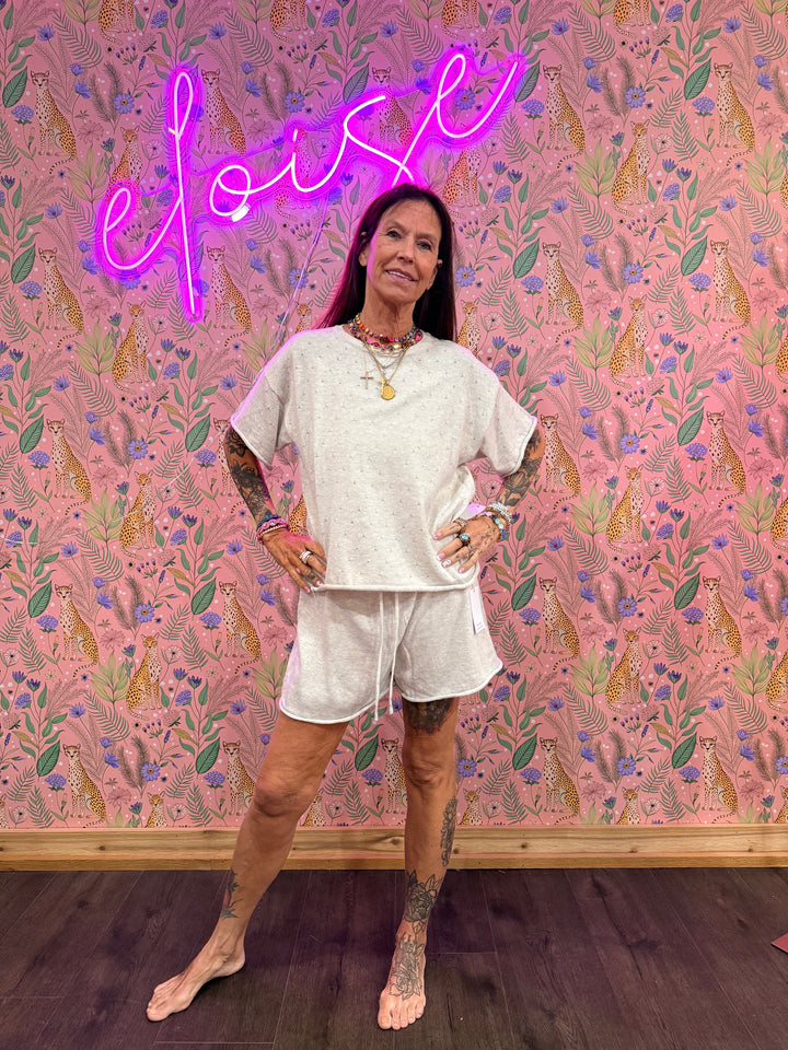 Woman wearing grey matching top and bottom on pink floral background