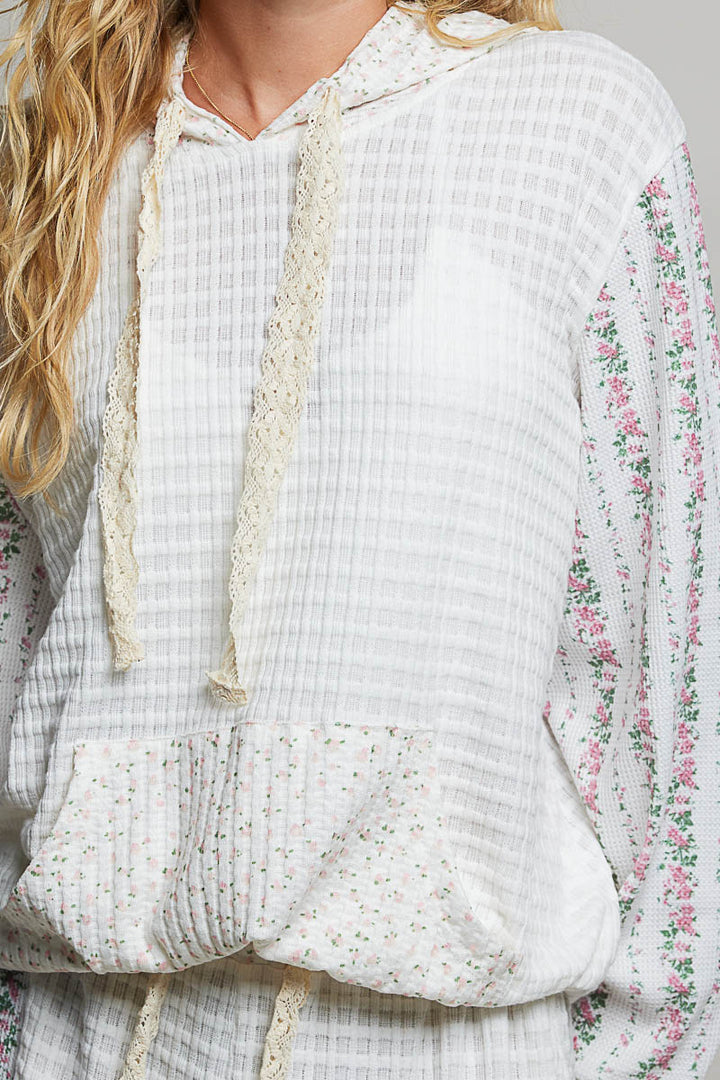 Close-up of a person wearing a white textured top with floral sleeves.