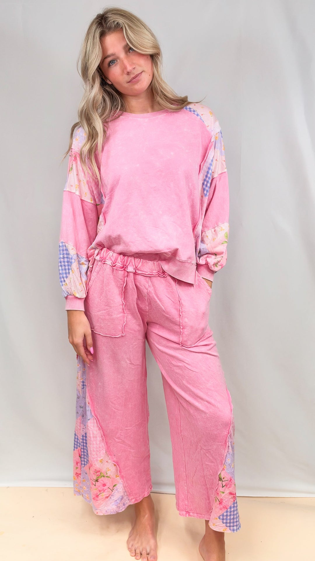 Woman wearing matching pink, patchwork top and bottom on plain background