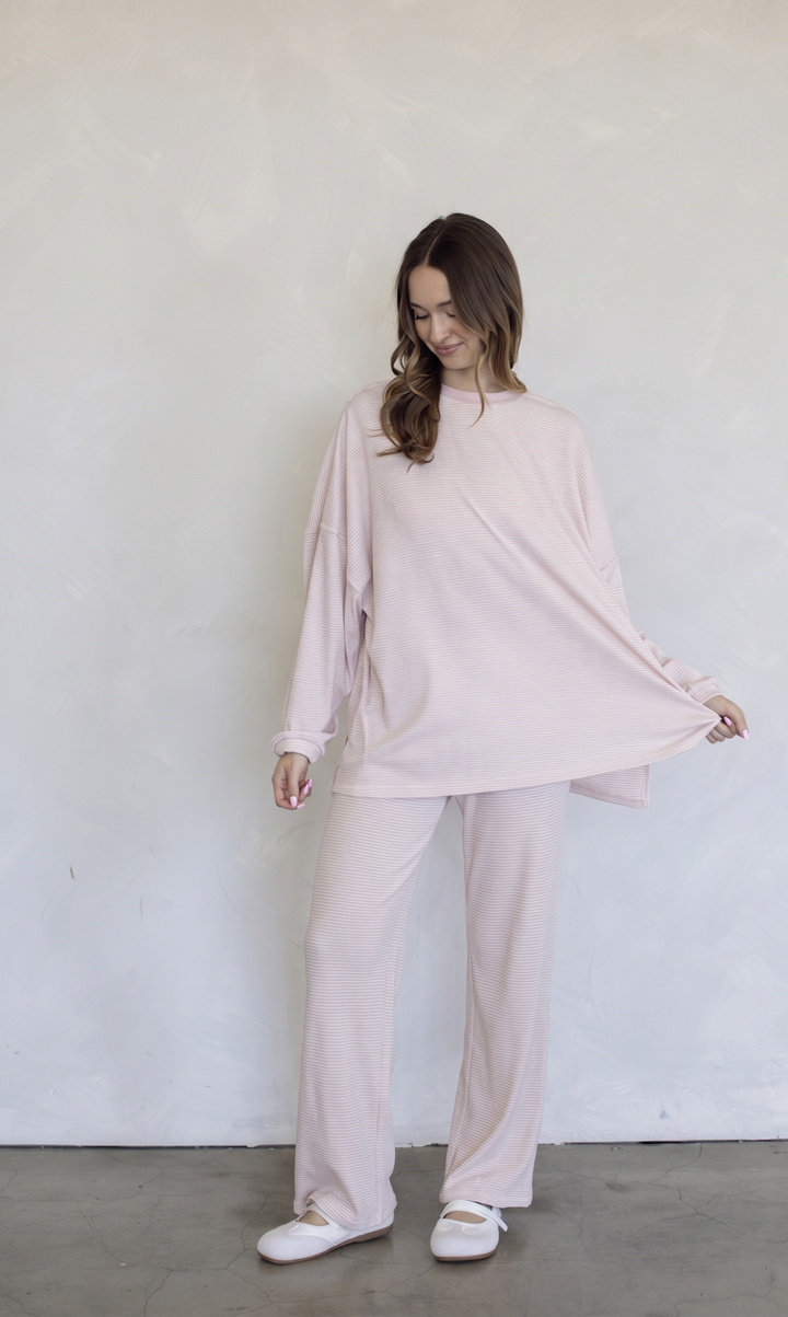 Woman wearing a light pink outfit against a white wall
