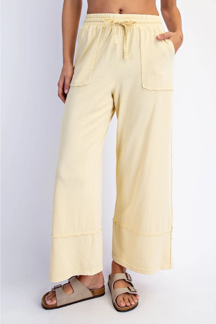 Person wearing light yellow wide-leg pants on a white background