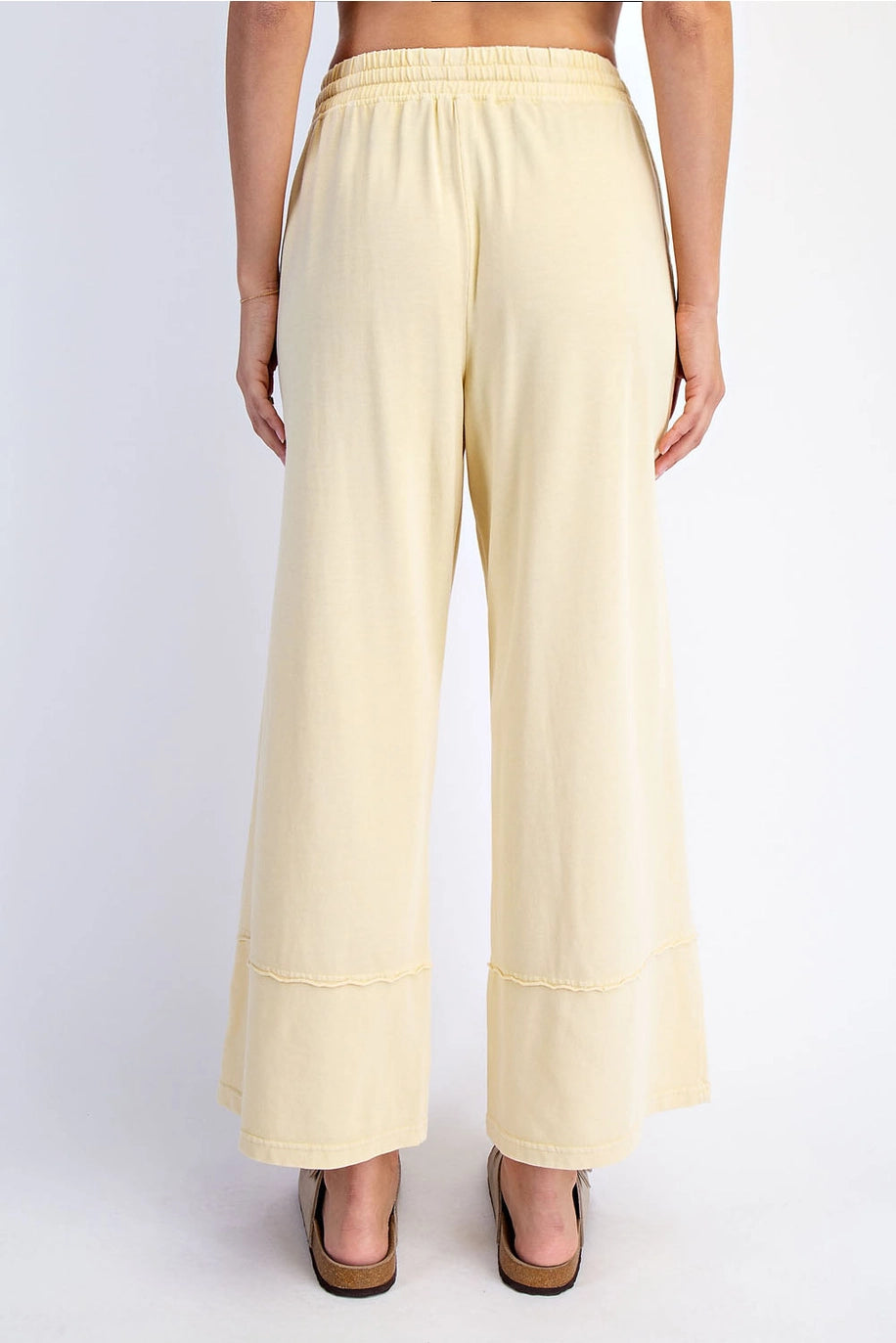 Light yellow wide-leg pants worn by a person on a white background