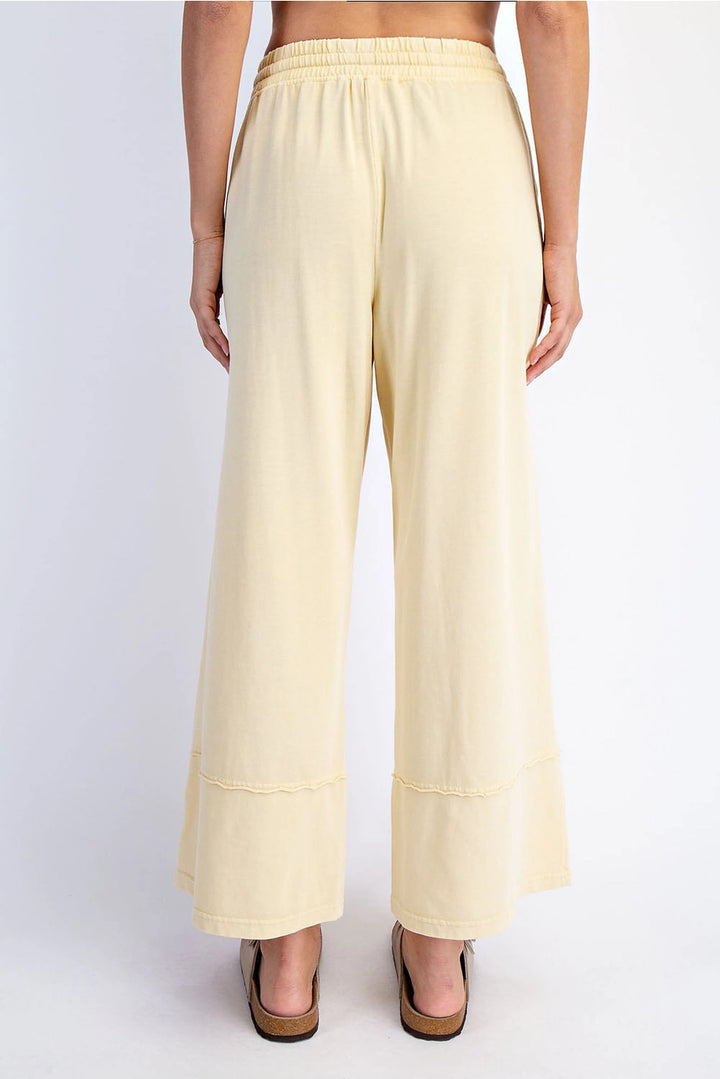 Light yellow wide-leg pants worn by a person on a white background