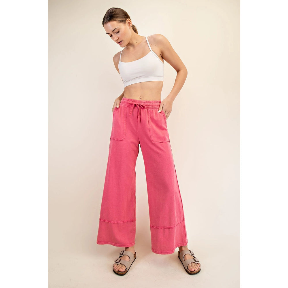 Woman wearing a white sports bra and pink wide-leg pants on a beige background