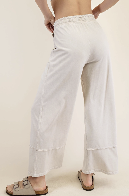 Person wearing white wide-leg pants on a plain background