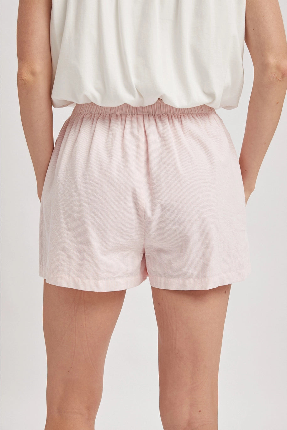 Back of person wearing pink boxer shorts on plain background