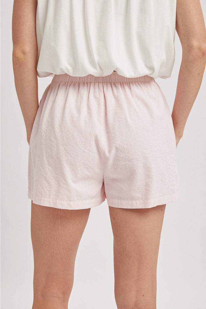 Back of person wearing pink boxer shorts on plain background