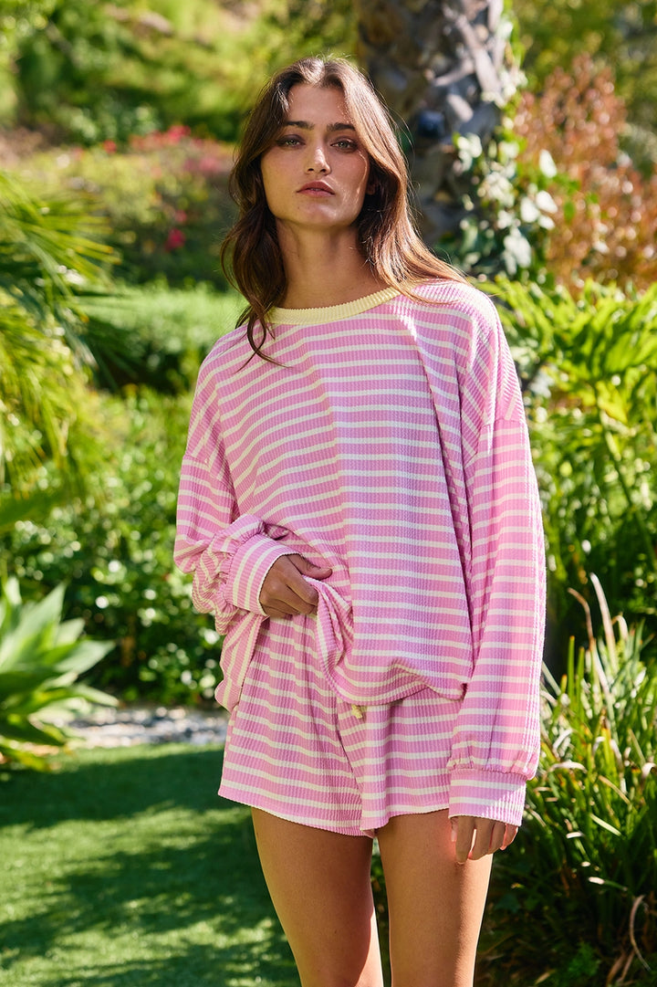 Woman wearing pink and white stripe top with yellow trim outdoors