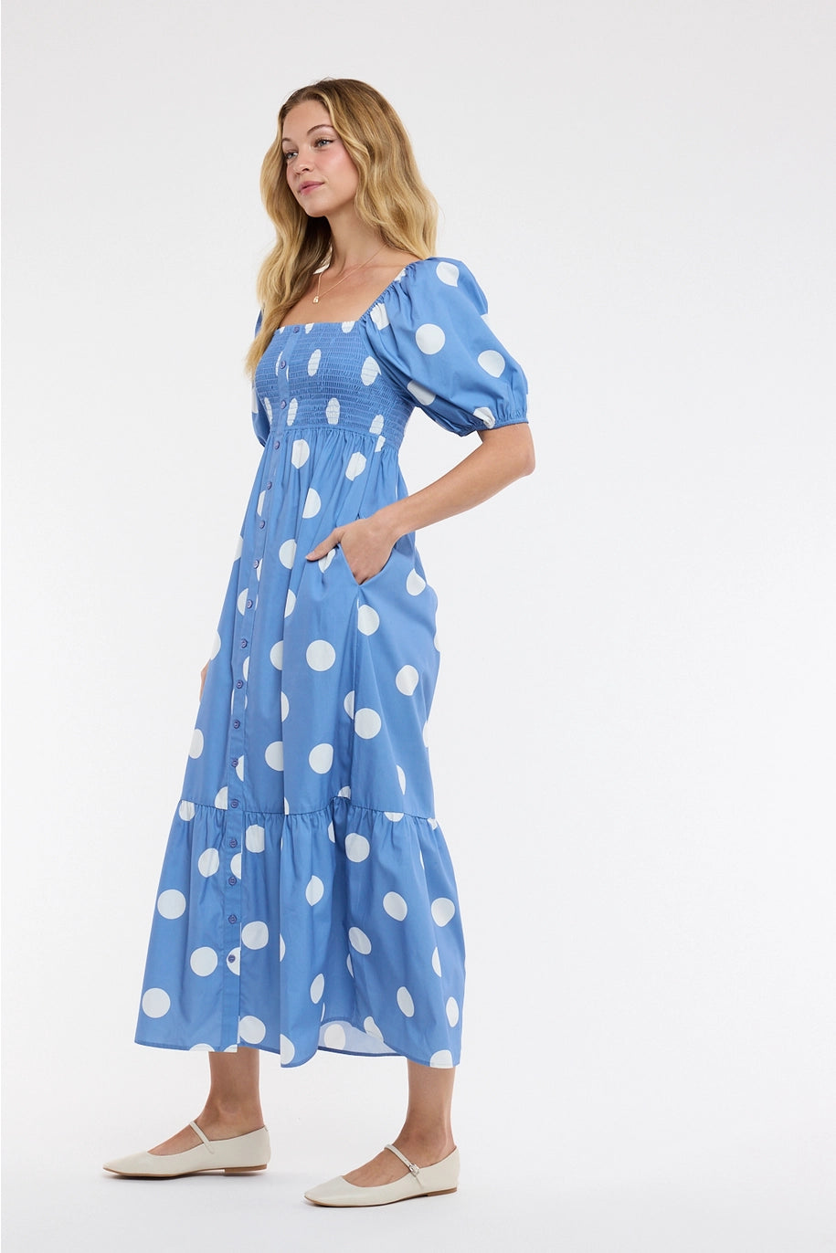 Woman wearing blue polka dot dress on plain background