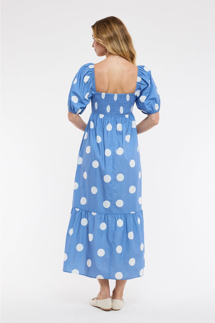 Back of woman wearing blue polka dot dress on plain background