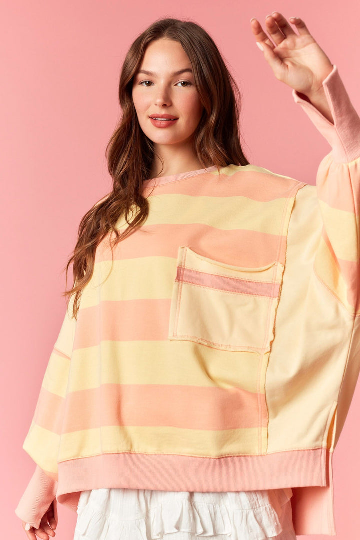 Woman wearing a colorful striped sweater against a pink background