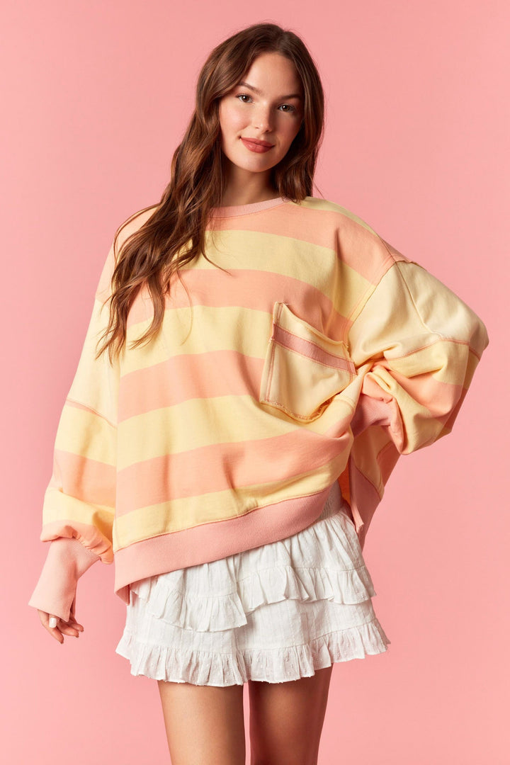 Woman wearing a colorful sweater and white skirt against a pink background