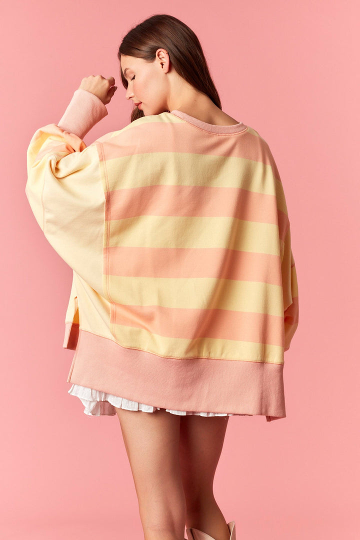 Woman wearing a colorful striped sweater against a pink background
