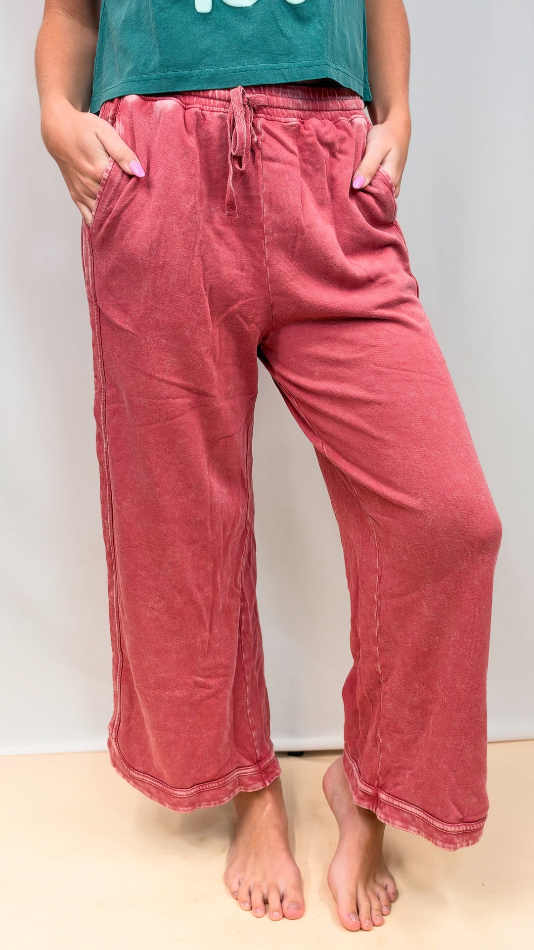 Woman wearing raspberry color sweatpants on plain background