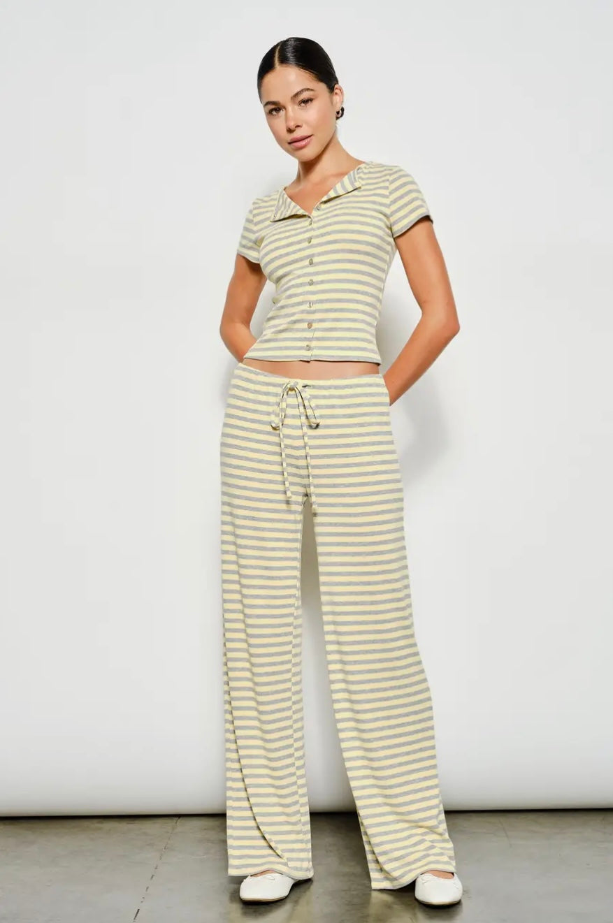 Woman wearing a striped outfit with wide-leg pants against a white background