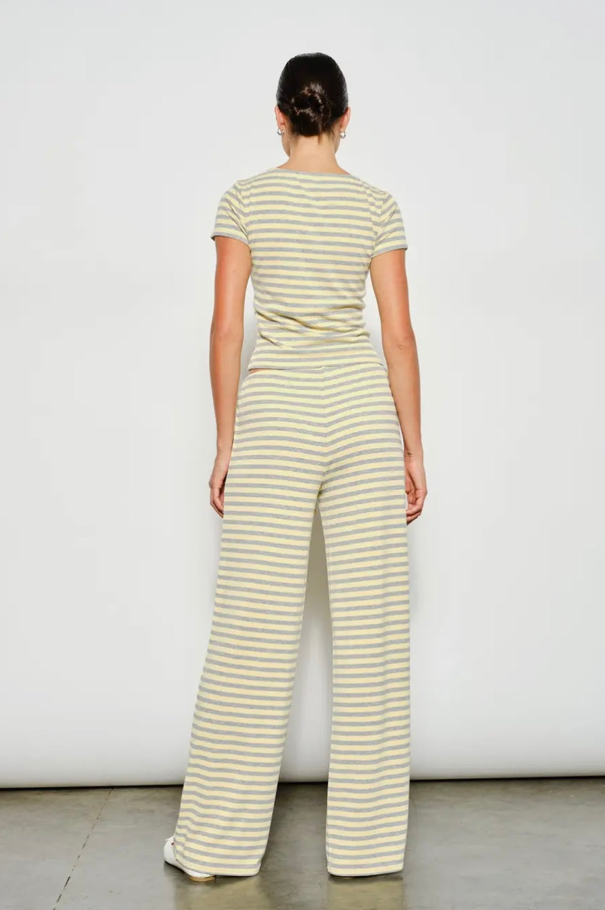 Woman wearing a yellow and white striped jumpsuit against a plain background