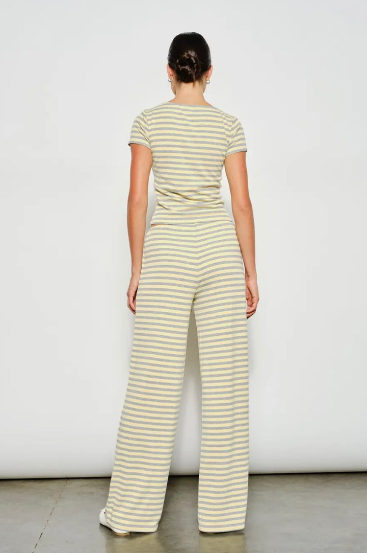Woman wearing a yellow and white striped jumpsuit against a plain background