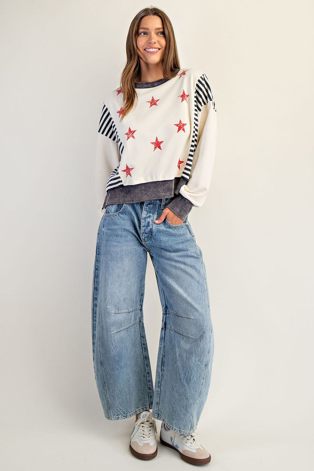 Woman wearing a sweater with star patterns and jeans on a plain background