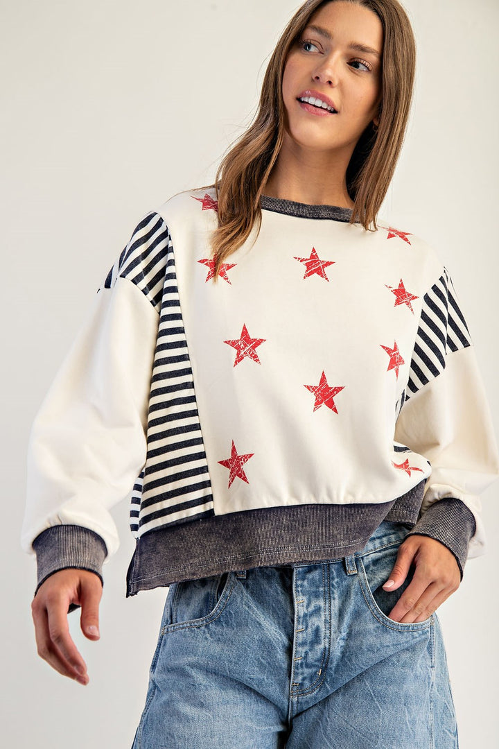 Woman wearing a sweater with star patterns and striped sleeves on a plain background