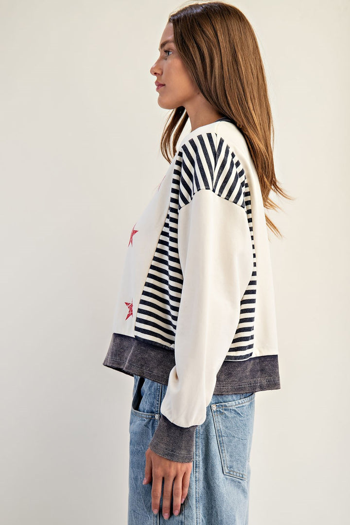 Woman wearing a striped sweater and jeans against a plain background