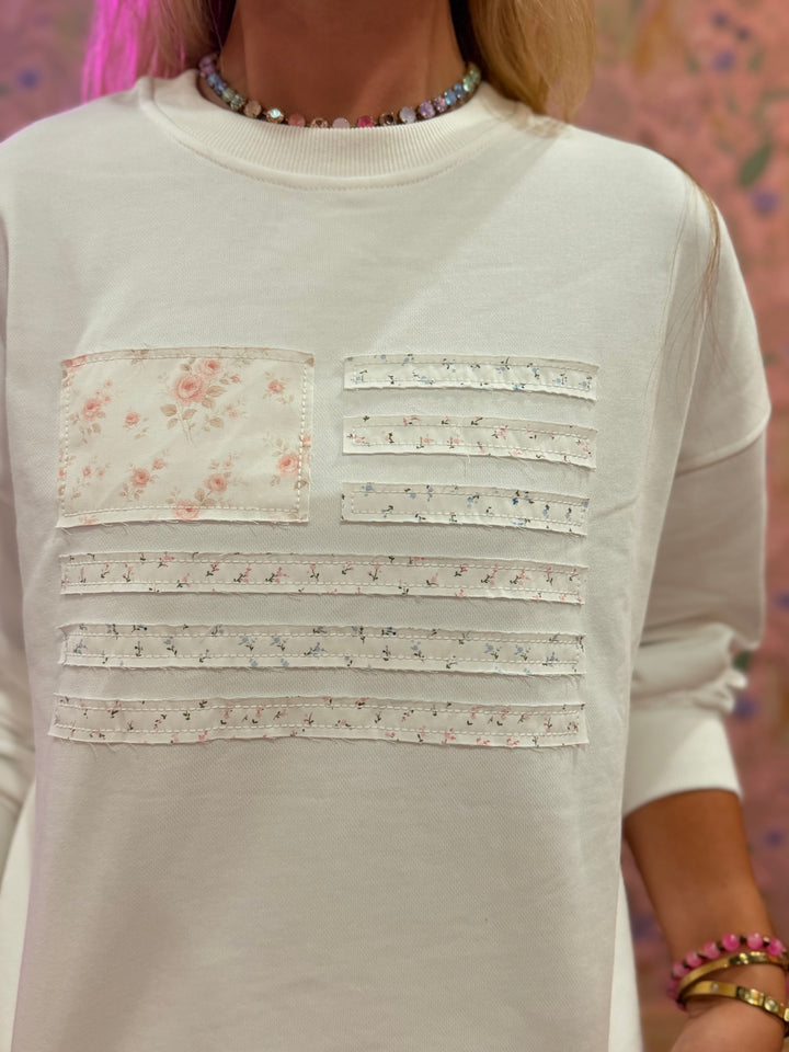 White sweater with floral and stripe patterns on a blurred background