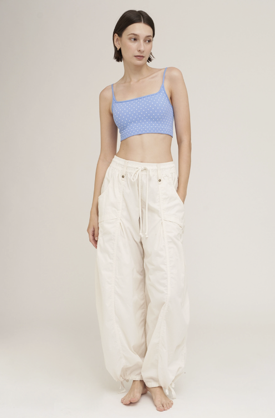 Woman wearing light blue bra with white polka dots with khaki pants on plain background