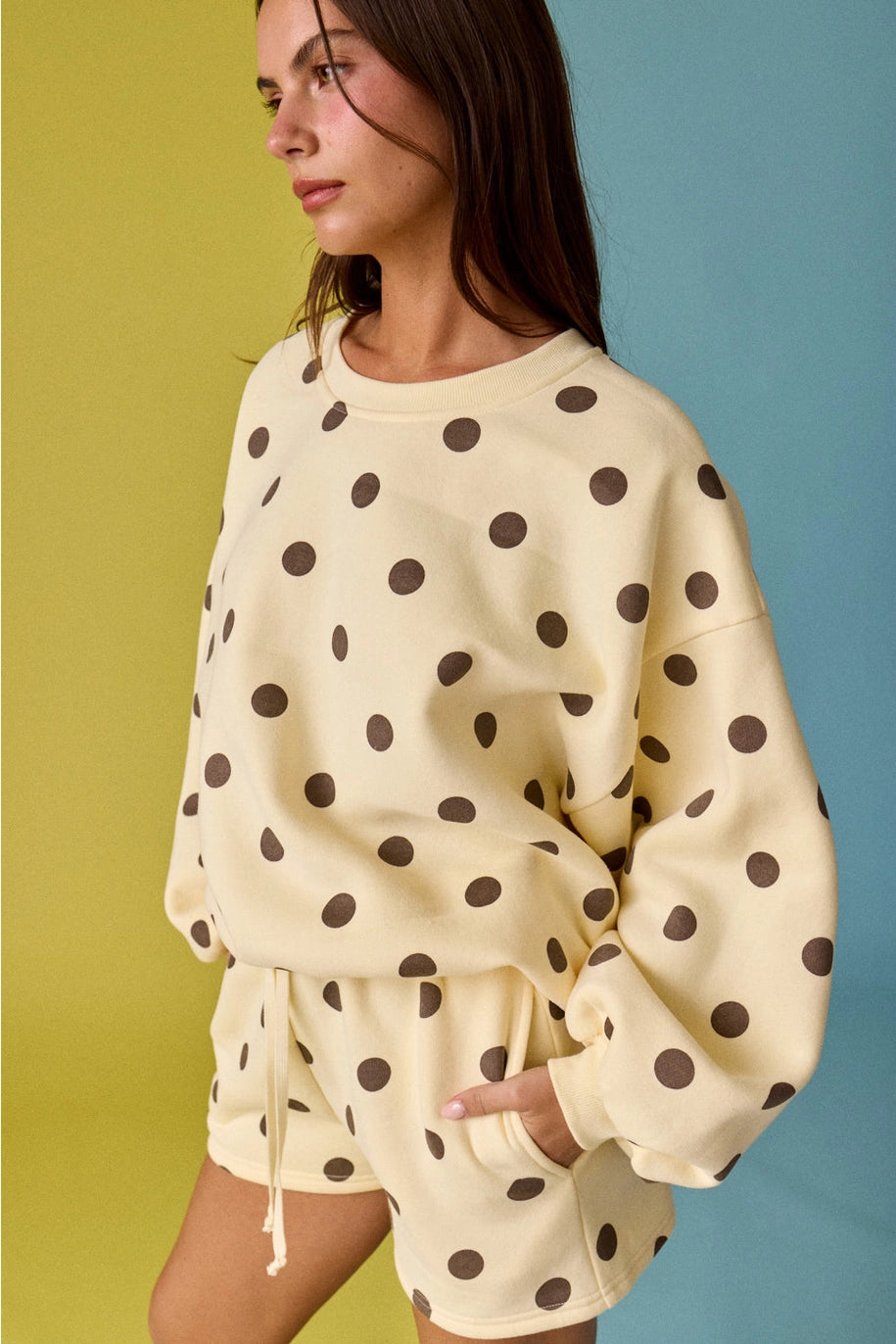 Woman wearing a polka dot outfit against a multicolored background