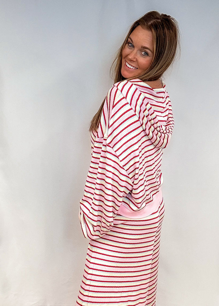 Woman showing back of pink, maroon, yellow and blue stripe matching set on white background